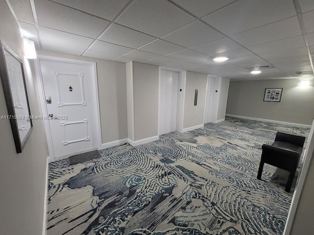 hallway featuring baseboards and a drop ceiling