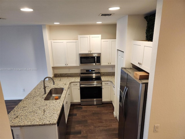 kitchen with sink, light stone counters, white cabinetry, and stainless steel appliances