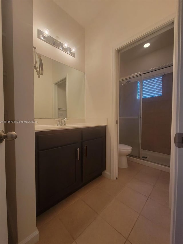 bathroom featuring tile patterned flooring, vanity, toilet, and walk in shower