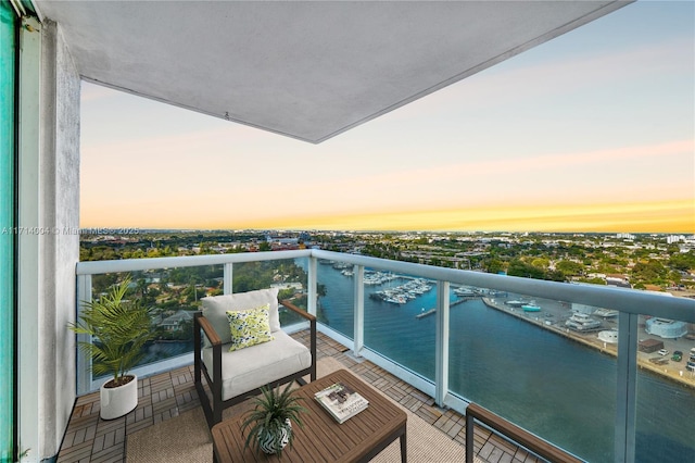 balcony at dusk featuring a water view