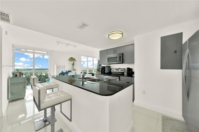 kitchen featuring sink, appliances with stainless steel finishes, a kitchen breakfast bar, electric panel, and light tile patterned flooring