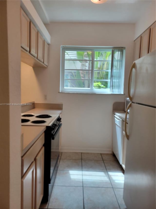 kitchen featuring light brown cabinets, light tile patterned flooring, and white appliances