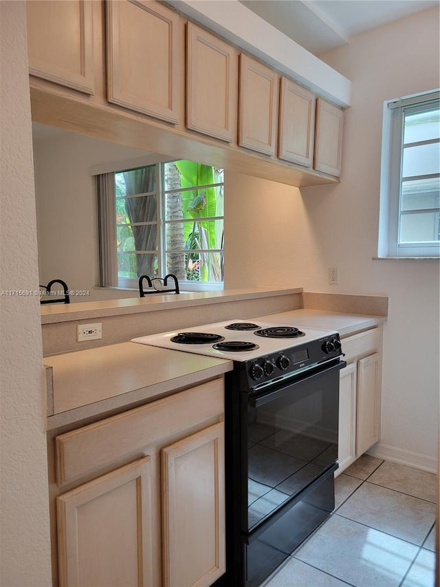 kitchen with black electric range oven and light tile patterned floors