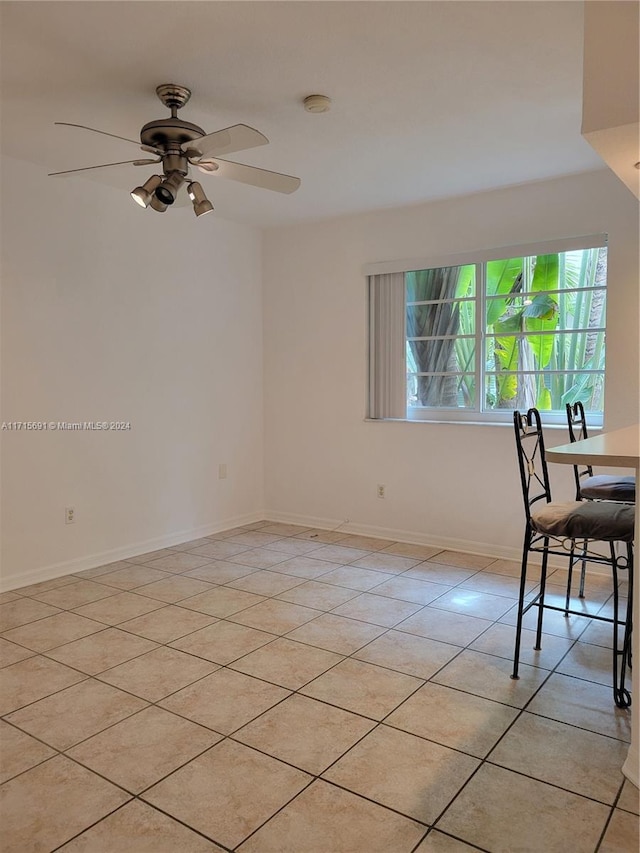 tiled spare room featuring ceiling fan