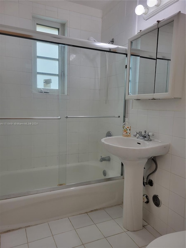 bathroom featuring tile patterned floors, toilet, shower / bath combination with glass door, decorative backsplash, and tile walls