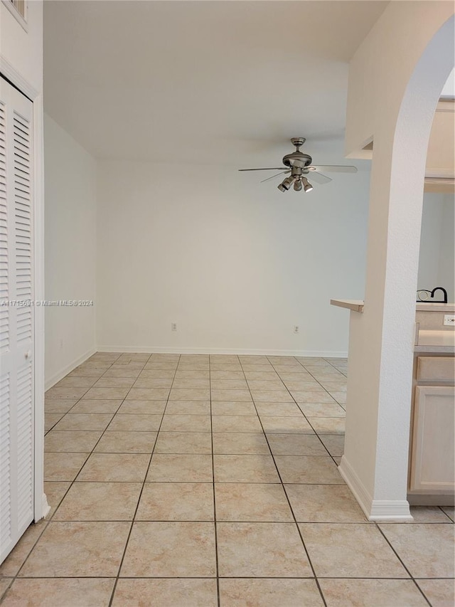 tiled empty room featuring ceiling fan