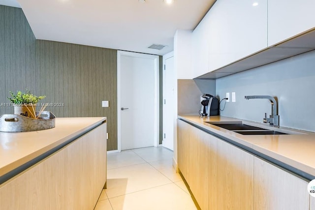 kitchen with white cabinets, light brown cabinets, light tile patterned floors, and sink