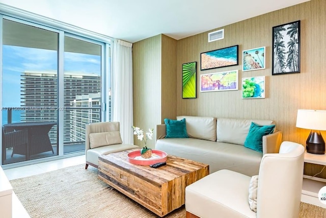 living room with tile patterned flooring, a water view, and expansive windows