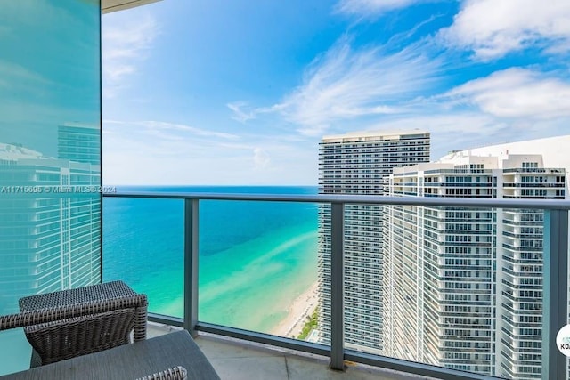 balcony featuring a view of the beach and a water view