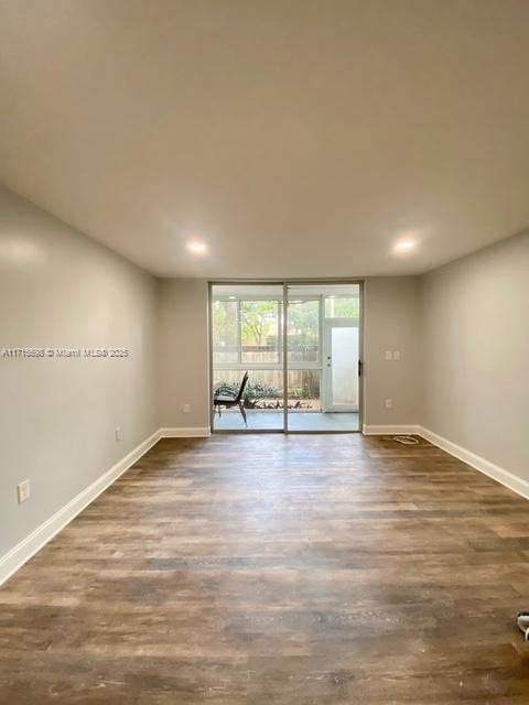 spare room featuring floor to ceiling windows and dark hardwood / wood-style floors