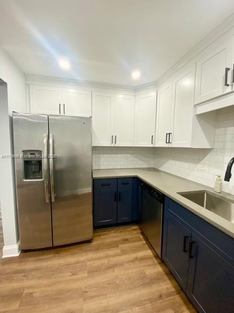 kitchen with blue cabinets, sink, stainless steel appliances, light hardwood / wood-style floors, and white cabinets