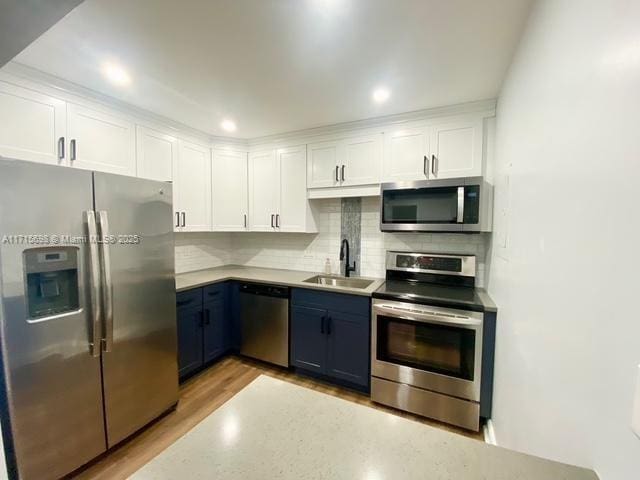 kitchen featuring blue cabinets, sink, appliances with stainless steel finishes, decorative backsplash, and white cabinets