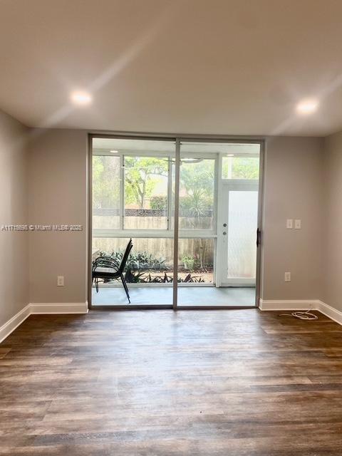 spare room with expansive windows and dark wood-type flooring