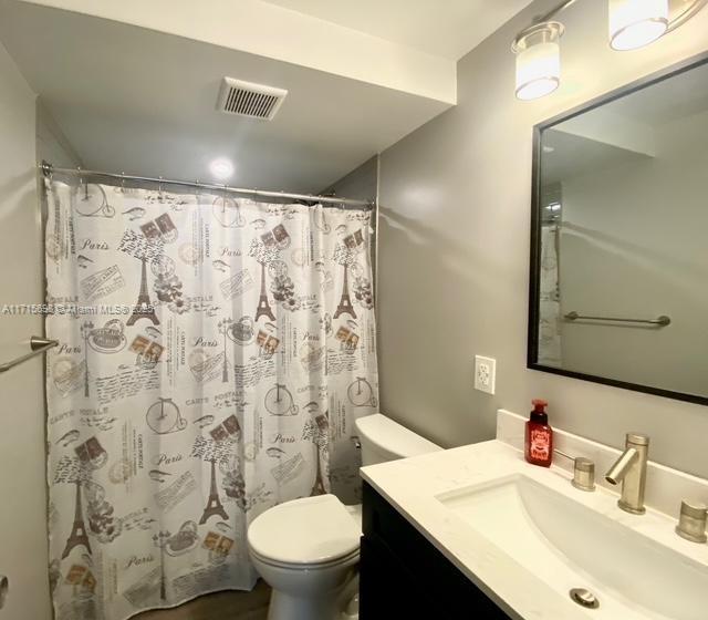 bathroom featuring vanity, a shower with shower curtain, and toilet