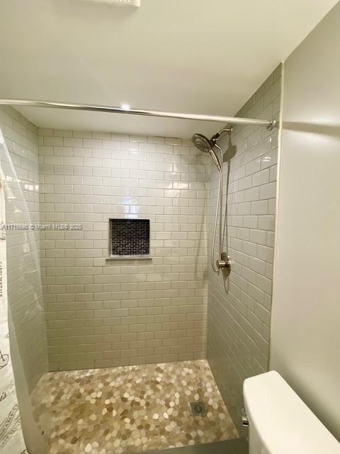 bathroom with toilet and a tile shower