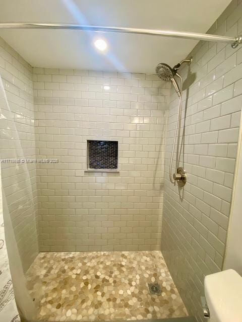 bathroom with toilet and a tile shower