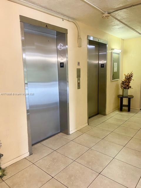 hall with elevator and light tile patterned flooring