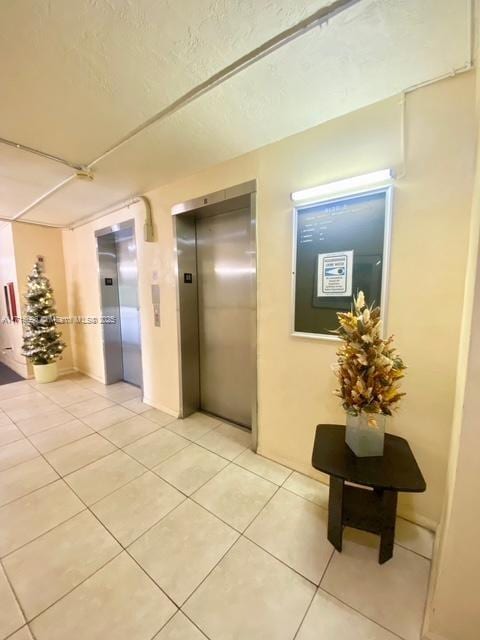 hall with elevator and light tile patterned floors