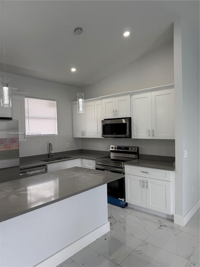 kitchen featuring white cabinets, hanging light fixtures, sink, vaulted ceiling, and appliances with stainless steel finishes