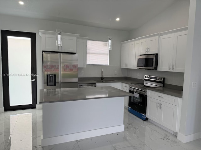 kitchen with appliances with stainless steel finishes, sink, decorative light fixtures, white cabinets, and a kitchen island