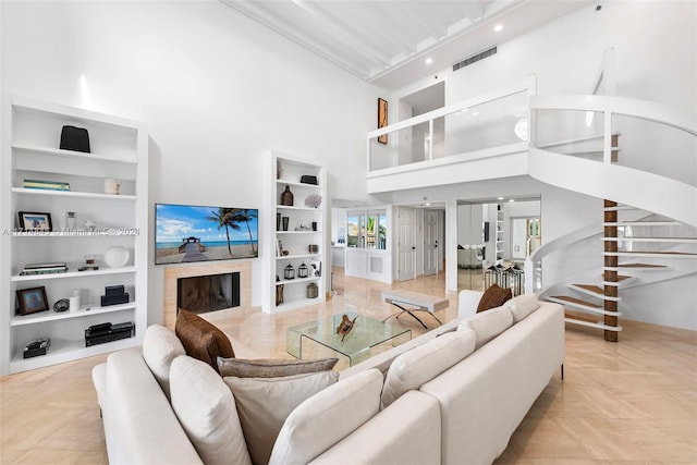 living room with built in features, french doors, a towering ceiling, and light parquet floors