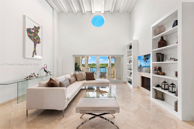 living room featuring beamed ceiling, french doors, a towering ceiling, and built in shelves