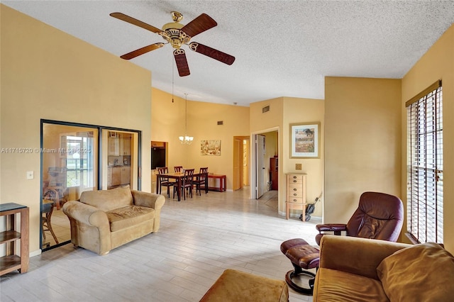 living room featuring ceiling fan with notable chandelier and a textured ceiling