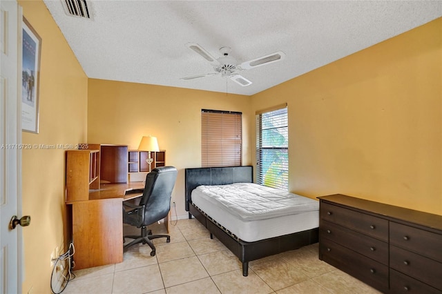 bedroom featuring ceiling fan, light tile patterned floors, and a textured ceiling