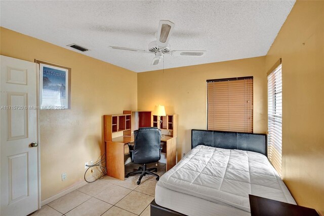 tiled bedroom featuring ceiling fan and a textured ceiling