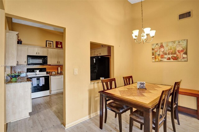 dining room with a chandelier, a high ceiling, and light hardwood / wood-style floors