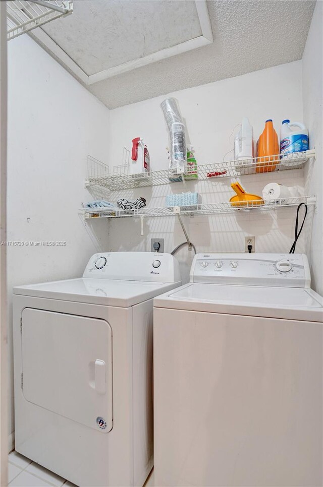 laundry area with light tile patterned floors, washing machine and dryer, and a textured ceiling