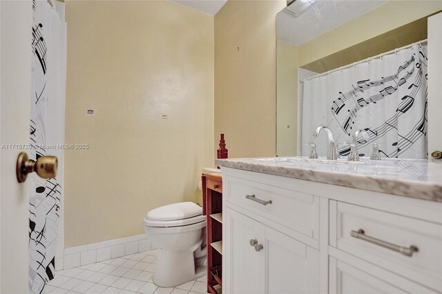 bathroom with tile patterned flooring, a textured ceiling, vanity, and toilet