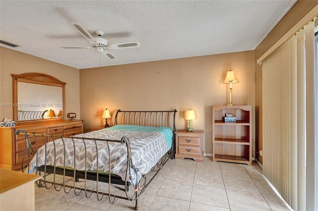 bedroom with ceiling fan, tile patterned flooring, and a textured ceiling