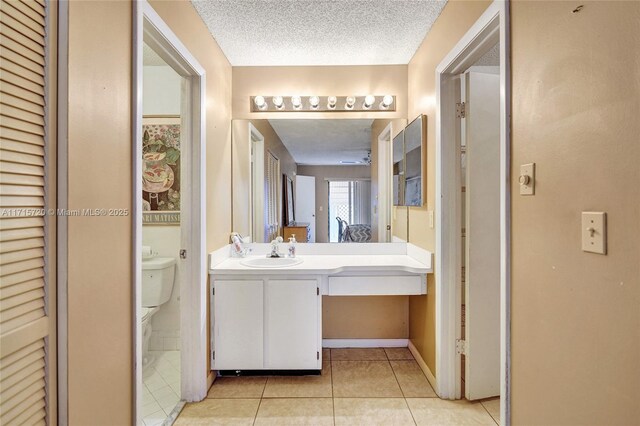 bathroom featuring tile patterned flooring, vanity, toilet, and a textured ceiling