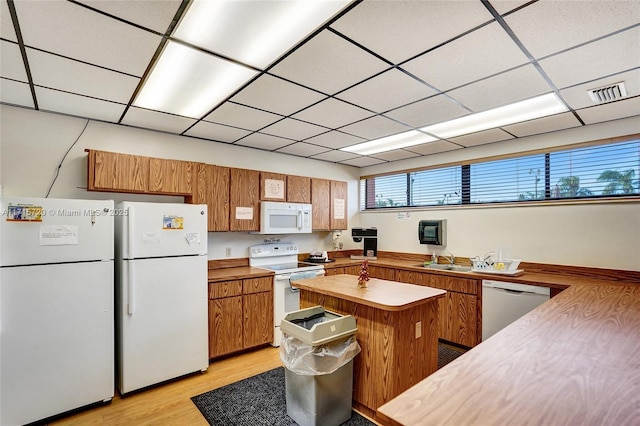 kitchen featuring kitchen peninsula, white appliances, light hardwood / wood-style flooring, and a paneled ceiling