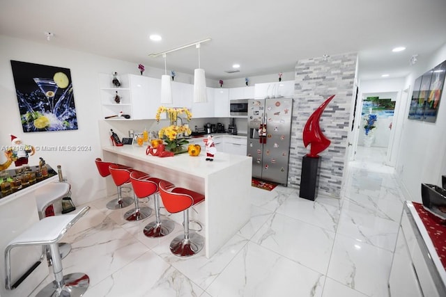 kitchen featuring pendant lighting, a breakfast bar, white cabinets, and stainless steel appliances