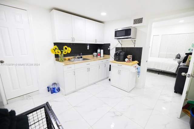 kitchen with white cabinets, decorative backsplash, and sink