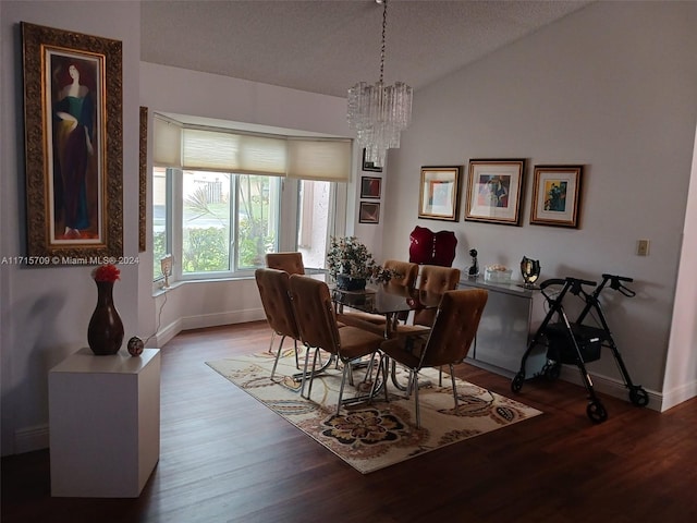 dining room with a textured ceiling, hardwood / wood-style floors, a chandelier, and lofted ceiling