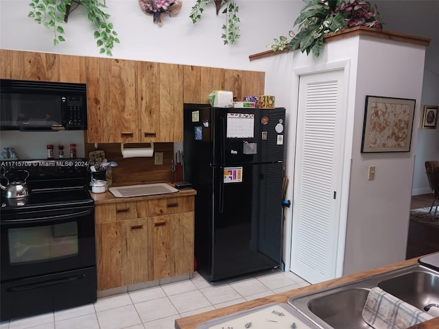 kitchen featuring sink, light tile patterned floors, and black appliances