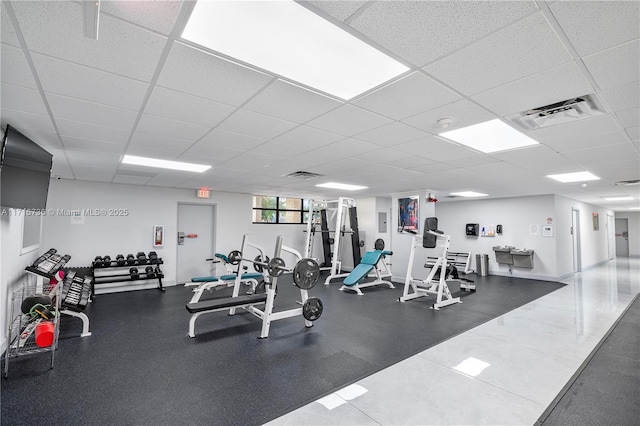 gym with visible vents, a paneled ceiling, and baseboards