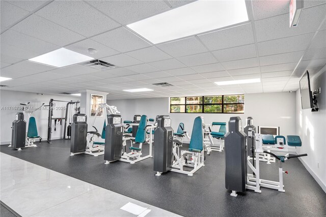 workout area featuring visible vents, a paneled ceiling, and baseboards