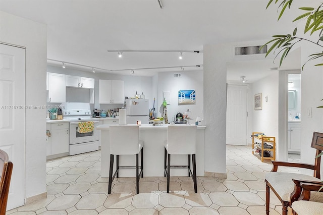 kitchen featuring visible vents, light countertops, a kitchen bar, white appliances, and white cabinetry