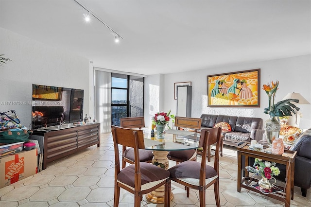 dining space featuring light tile patterned floors, track lighting, and a wall of windows