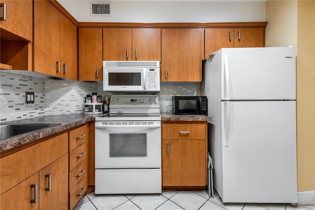 kitchen with white appliances, tasteful backsplash, dark stone counters, and light tile patterned flooring