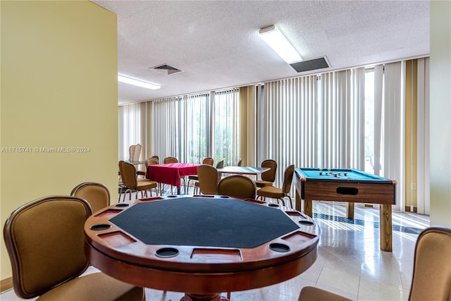 game room featuring a textured ceiling, a wall of windows, and pool table