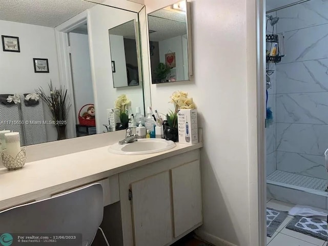 bathroom featuring vanity, a tile shower, and a textured ceiling