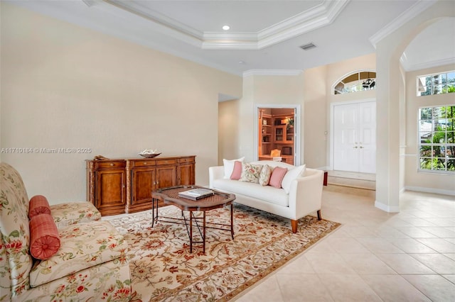 tiled living room with ornamental molding and a tray ceiling