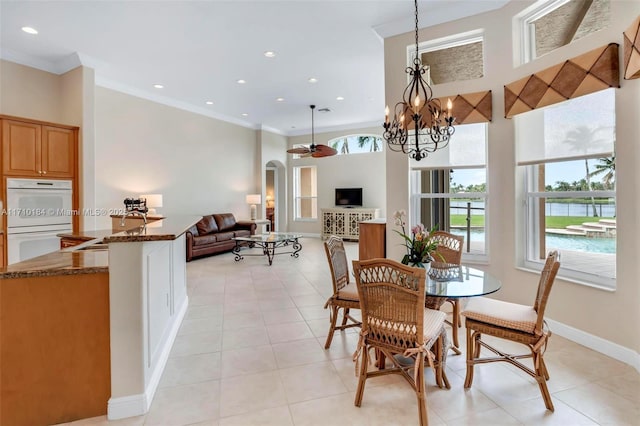 dining area featuring light tile patterned floors, ceiling fan with notable chandelier, crown molding, and sink