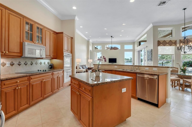 kitchen featuring white appliances, pendant lighting, stone counters, a chandelier, and a kitchen island