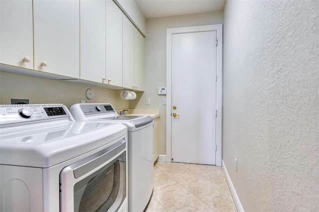 washroom with washing machine and clothes dryer, light tile patterned flooring, and cabinets